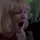 Drew Barrymore's Casey Becker in Scream opens her mouth wide to call out while the masked killer stalks her from behind.